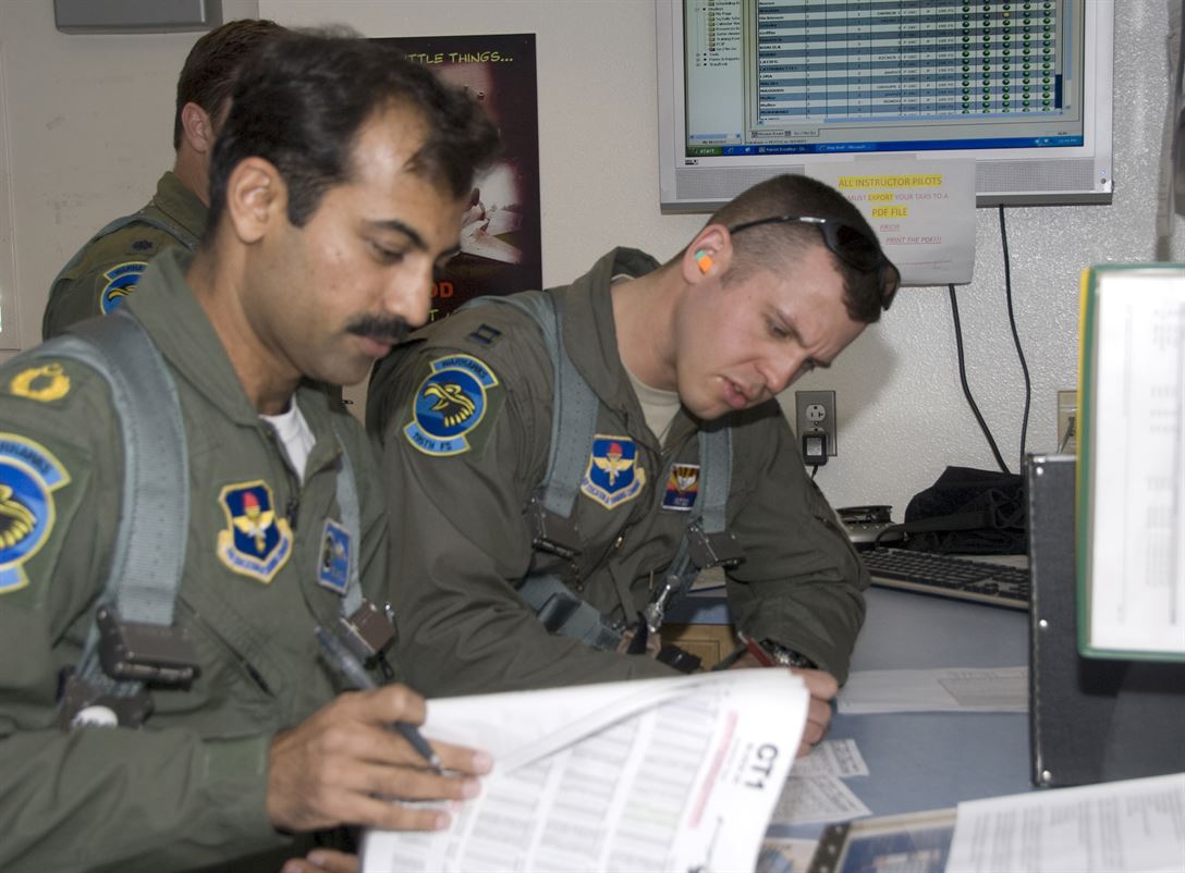 Squadron Leader Azman Khalil of the Pakistani air force, left, goes over flight information with Air Force Capt. Andy Wittke, an instructor pilot at the Arizona Air National Guard's 162nd Fighter Wing, before a training mission April 27,2010. U.S. Air Force photo by Master Sgt. Dave Neve
